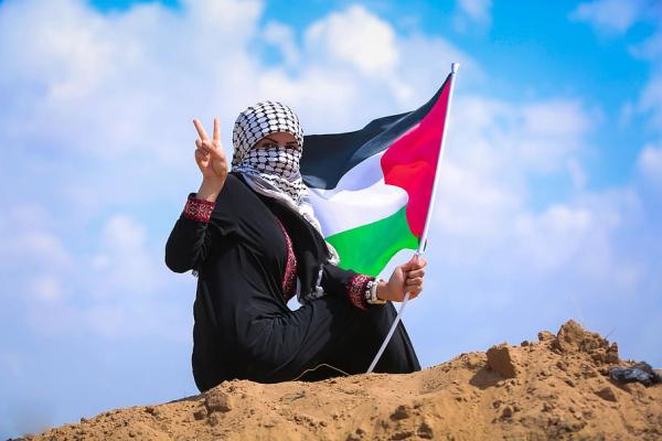 Kvinna med palestinaflagga gör fredstecknet